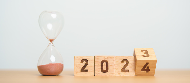 flipping block 2023 to 2024 text with hourglass on table. Resolution, time, plan, goal, motivation, reboot, countdown  and New Year holiday concepts