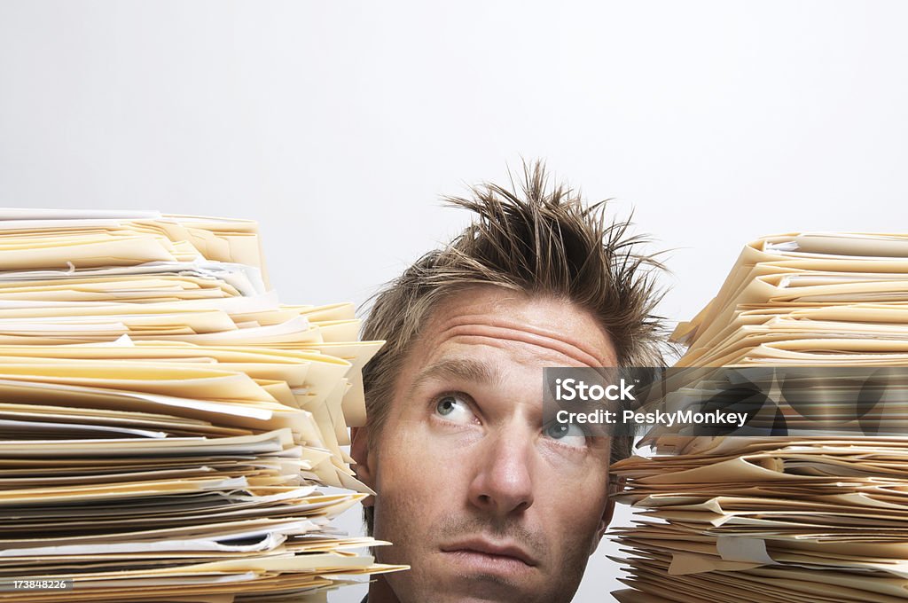 Uomo Sbirciare Up tra pile di documenti - Foto stock royalty-free di Catasta