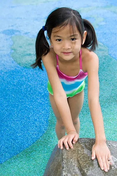 Chinese little girl playing outdoors in the water (shallow dof)