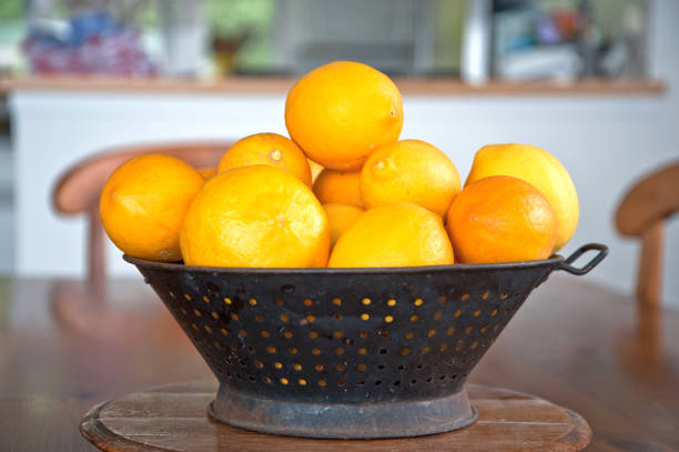 Lemons Antique metal bowl filled with lemons as centerpiece on table. antique fruit bowl stock pictures, royalty-free photos & images