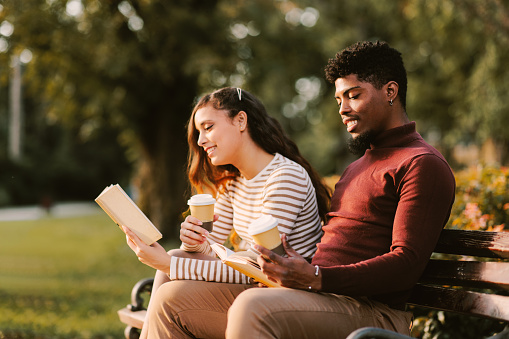 Young couple enjoying a park on a sunny day and reading a book