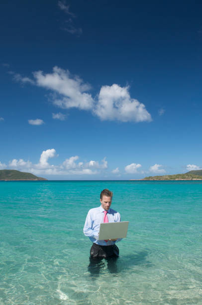 istock Businessman Stands Typing on Laptop in Tropical Waters 173848921