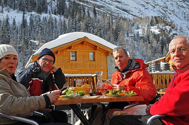 cuatro happy senior skiers con un almuerzo al aire libre - beer ski apres ski snow fotografías e imágenes de stock