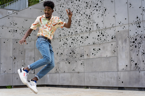 Horizontal photo with copy space of a stylish afro man jumping in the street