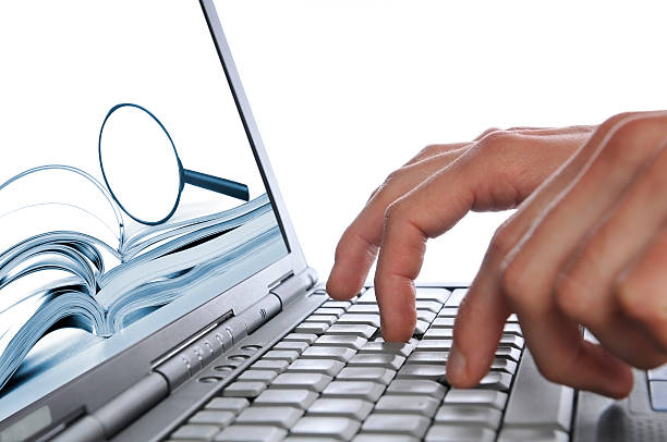 Searching internet, man's hands laptop keyboard, magnifying glass on screen