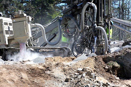 Two rock drilling machines in operation, preparing bore holes for blasting.