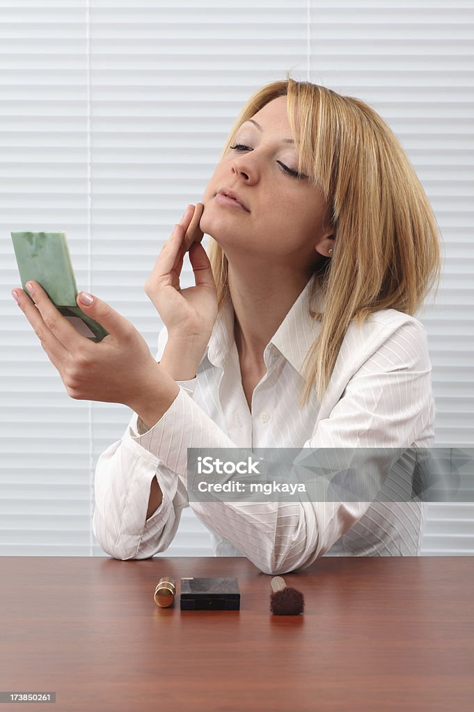 Young Woman Applying Makeup Young woman looking in mirror and applying makeup. Adult Stock Photo