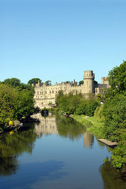 vertical picture of Warwick castle and river Avon Warwick Castle reflected in the river avon with lots of copy space. warwick uk stock pictures, royalty-free photos & images