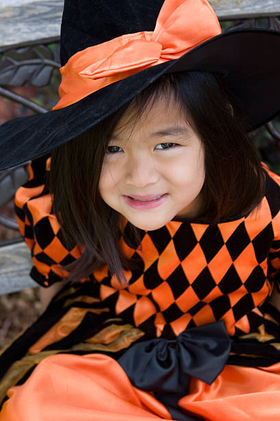Little girl in witch costume having fun outdoors on Halloween trick or treat