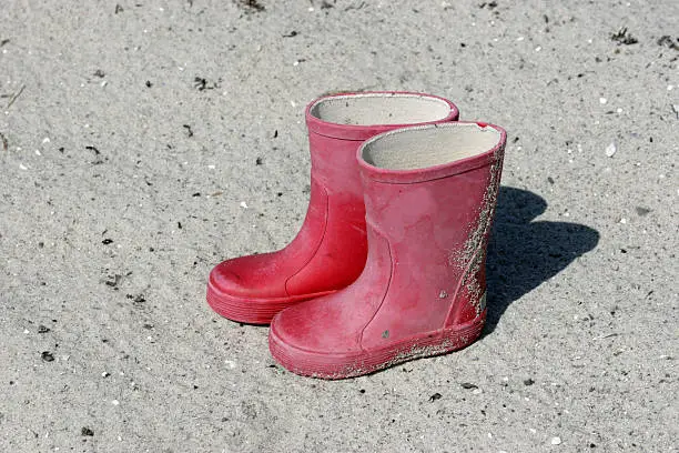 Childrens red rubberboots on beach
