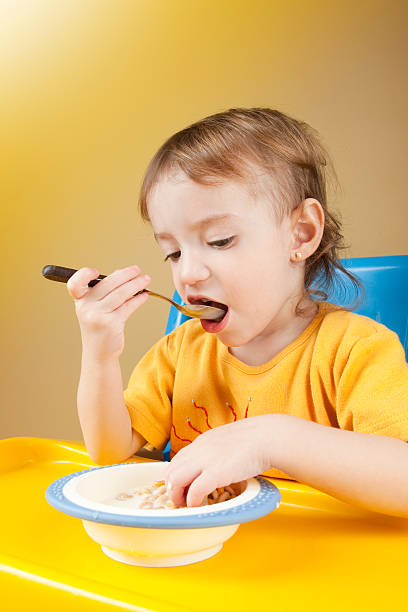 ребенок девочка ест cornflakes - eating cereal student human mouth стоковые фото и изо�бражения