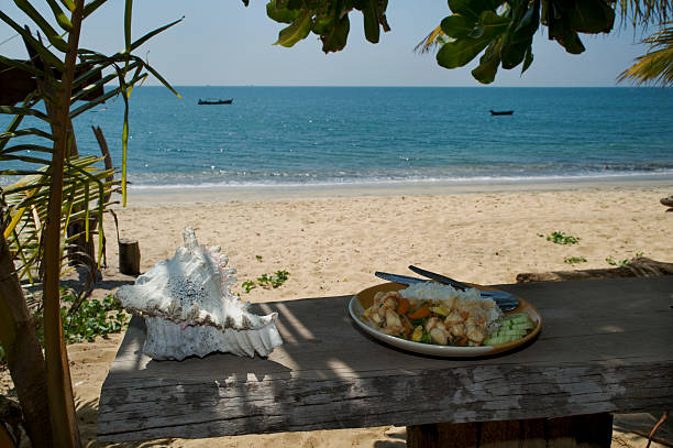 A plate of Thai food with the beach in the background.