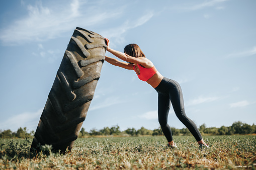 Fitness woman in training, lifting a wheel as part of her exercise routine. Training Female Athlete Exercising with a Wheel Outdoors
