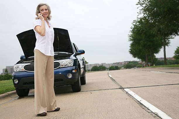 istock Senior Woman on her Cellphone by a Broken-down Car 173852402