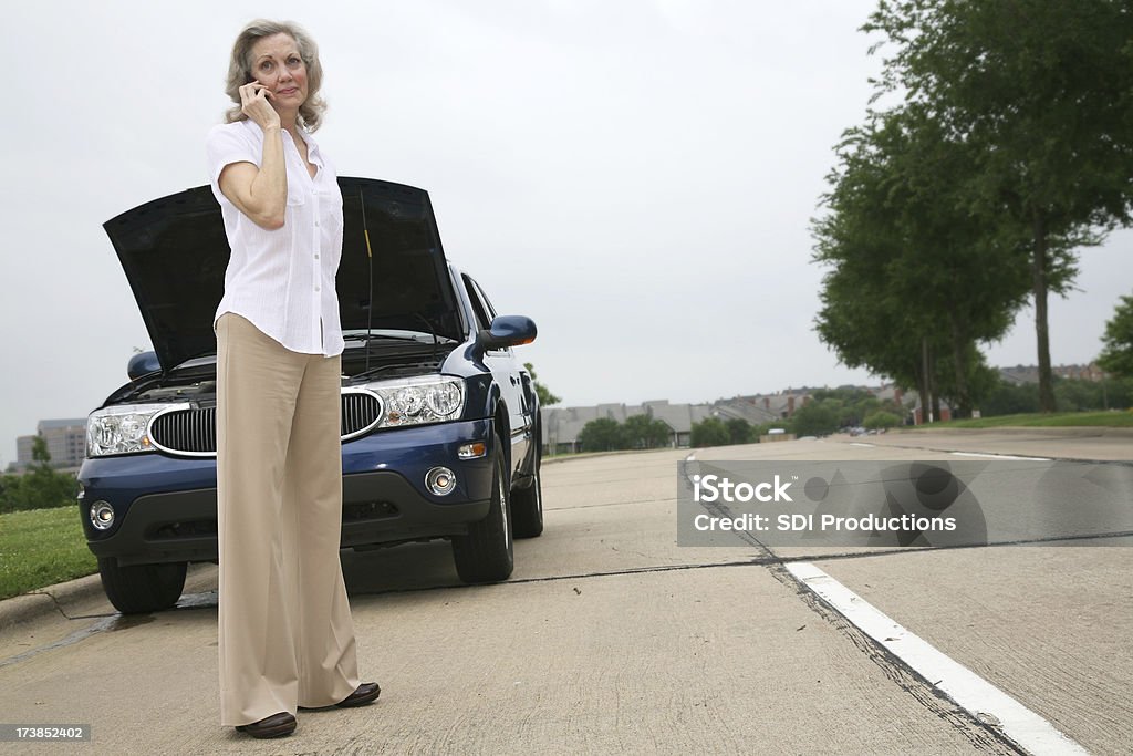 Starsza kobieta na jej komórkowy przez pęknięcia-W samochodzie - Zbiór zdjęć royalty-free (Awaria samochodu)