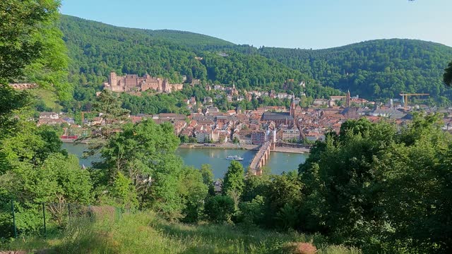 Hillside view of Heidelberg city center in Germany at Neckar river with castle palace and Theodor Bridge in a long wide shot