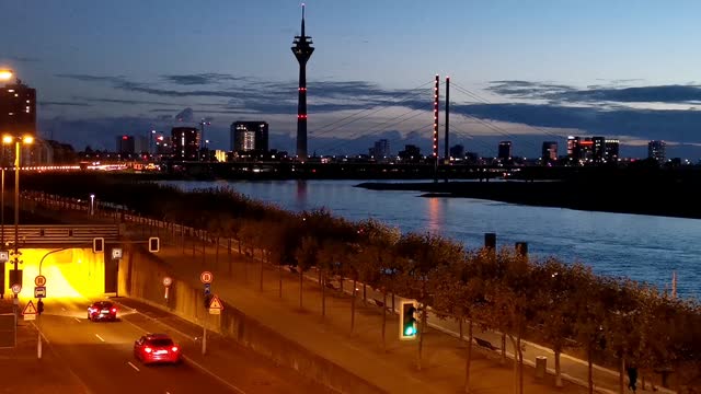 Time lapse Düsseldorf evening atmosphere with traffic and tunnel, promenade, Rhine tower and water