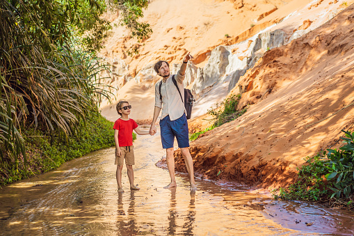 Father and son tourists on the Fairy stream among the red dunes, Muine, Vietnam. Vietnam opens borders after quarantine COVID 19.