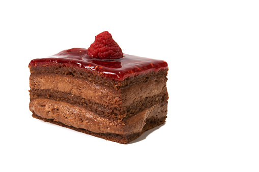 A sweet chocolate cream with a layer of raspberry jam and a raspberry on top, isolated on white background.