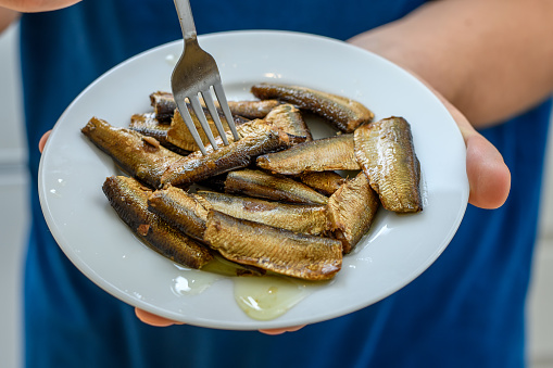 Delicious smoked sprats in oil on a white plate closeup isolated