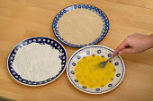 The ingredients for the breading are on plates - flour, breadcrumbs and egg