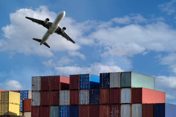 istock Many cargo containers in an open-air warehouse with a plane taking off in the background. 1738566867