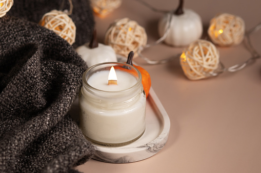 Handmade coconut wax candle in a glass jar, autumn decorations with pumpkins, decor of cozy home interior