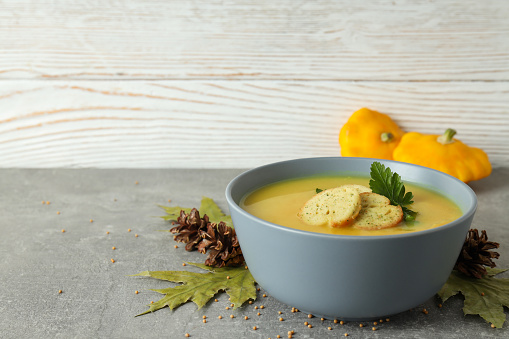 Concept of tasty food with pumpkin soup on gray textured table