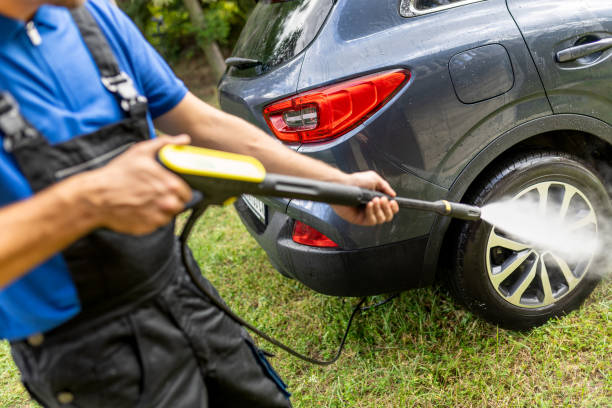 istock Man using water pressure washer to clean his car outside. 1738584121