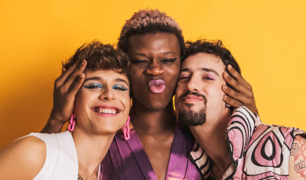 multiethnic LGBTQ people smiling at the camera together on yellow stock photo