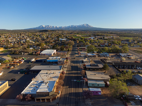 Panoramic view of the small rural town of Blanding, Utah in the spring blossom time, blue sky and snowcapped mountains. Drone view, early morning sun.