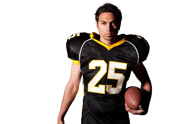 portrait of intent high school or college athlete with black white and yellow uniform holding american football isolated on white background