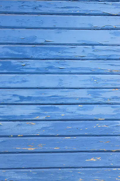 Grungy flaky blue paint background on a wooden fence.