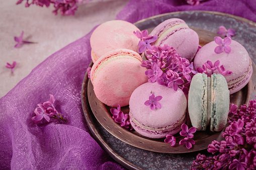 istock Sweet pastel french macaroons and lilac flowers on gray background 1738618857