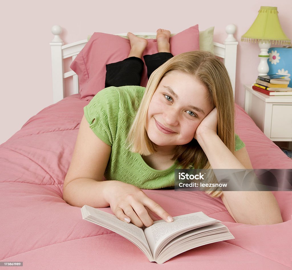 Ragazza sdraiata sul letto leggendo - Foto stock royalty-free di Adolescente