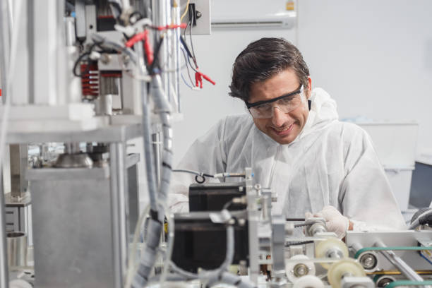 istock Man maintenance worker, face mask production machine. Male engineer wearing protective suit Inspecting quality of masks. Machine production manufacturing factory. 1738620645