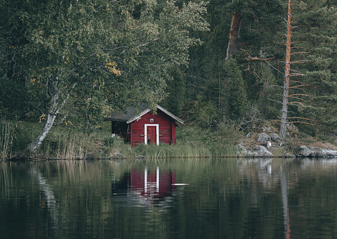 Small red wooden house on the shore of a lake in Finland