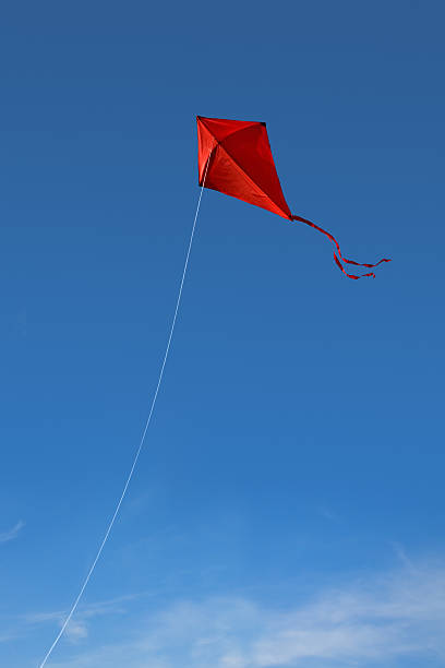 A red kite flying against a vivid blue sky