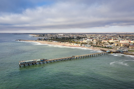 Namibia Swakopmund Jetty. Aerial Drone View of the famous Swakopmund Jetty Bridge - Pier of Swakopmund over the South Atlantic Ocean. Swakopmund Coast Beach under moody summer sky. Aerial Drone Point of View, South Atlantic Ocean, Swakopmund, Erongo Region, Namibia, Africa.