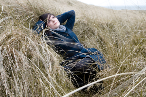 Girl taking a rest in the windswept grass. Fashion