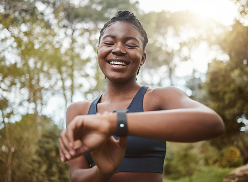 African runner woman, smart watch and park for check, smile or happy for time, results or fitness in nature. Girl, iot clock and monitor for speed, heart rate or smile for exercise, workout or health
