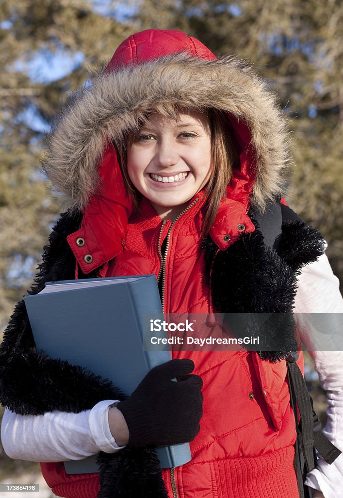 Smiling Female Student Outdoors Holding School Text Book Smiling young woman with furry hood carrying a book. 14-15 Years Stock Photo