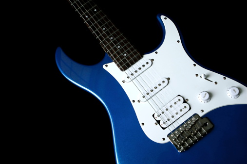 An electric blue electric guitar on a black background. Copy space.