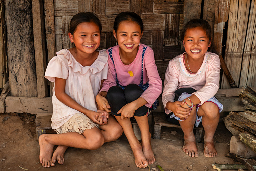Three Laotian little girls sitting on a stairs in a village in Northern Laos