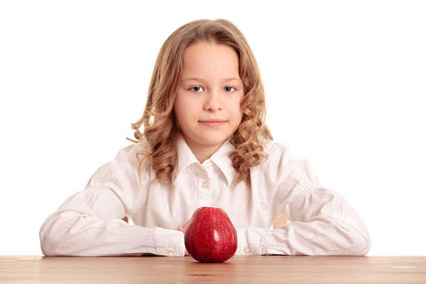 Sweet lesson: Girl with an apple - a symbol of health and education against the backdrop school blackboard.