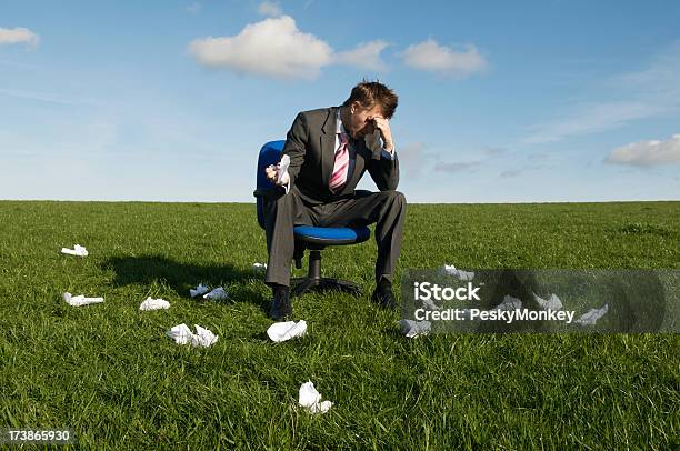 Frustrated Businessman Sitting In Meadow With Rejected Crumpled Paper Stock Photo - Download Image Now