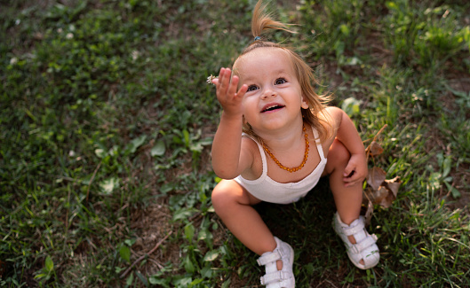 Baby girl pointing her finger, excited and emotional, on neutral background