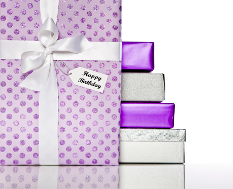 Pretty purple birthday gifts with white satin ribbon, isolated on white.