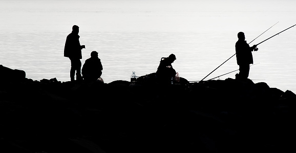 The Fascinating Silhouette of Amateur Fishermen on the Rocks Against the Sky. Nature. Seaside.Morning time.