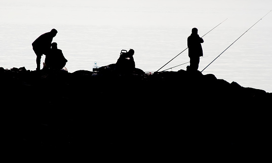 The Fascinating Silhouette of Amateur Fishermen on the Rocks Against the Sky. Nature. Seaside.Morning time.